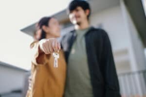 Asian young couple happy just received house key for their new house.